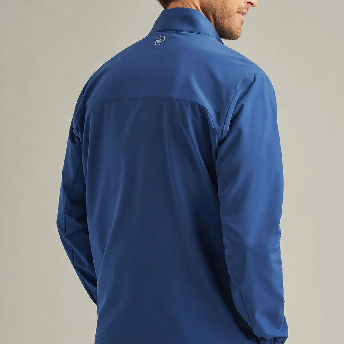 lifestyle image of male model wearing the jacket showing the back.  Peter Millar logo at the top center.