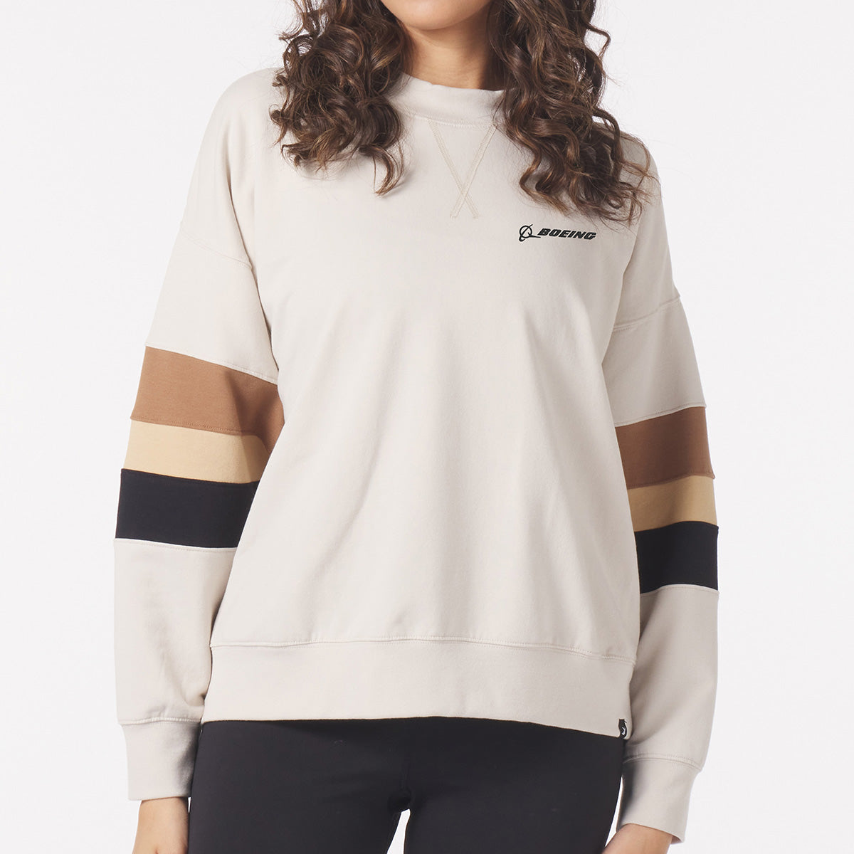 Full product image of the over-sized crewneck sweater in oatmeal color.  Black Boeing signature logo on left chest.  Features a black, tan, brown stripe on both arms near the elbow area. 