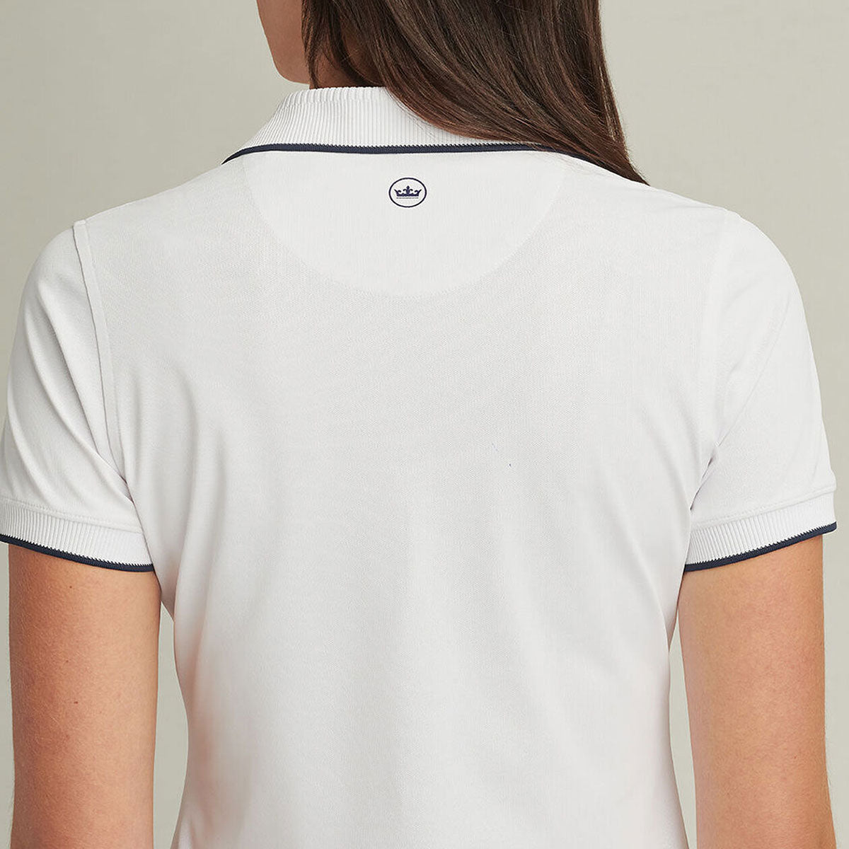 Women wearing the white polo showing the back of the polo.  Peter Millar logo on the back of the neck area.