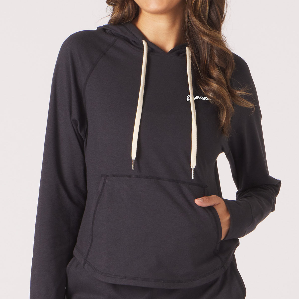 Lifestyle image of Glyder hooded sweatshirt in black. White Boeing signature logo on left chest.  White hood strings and pouch pocket.  Glyder logo on lower left hip area. 